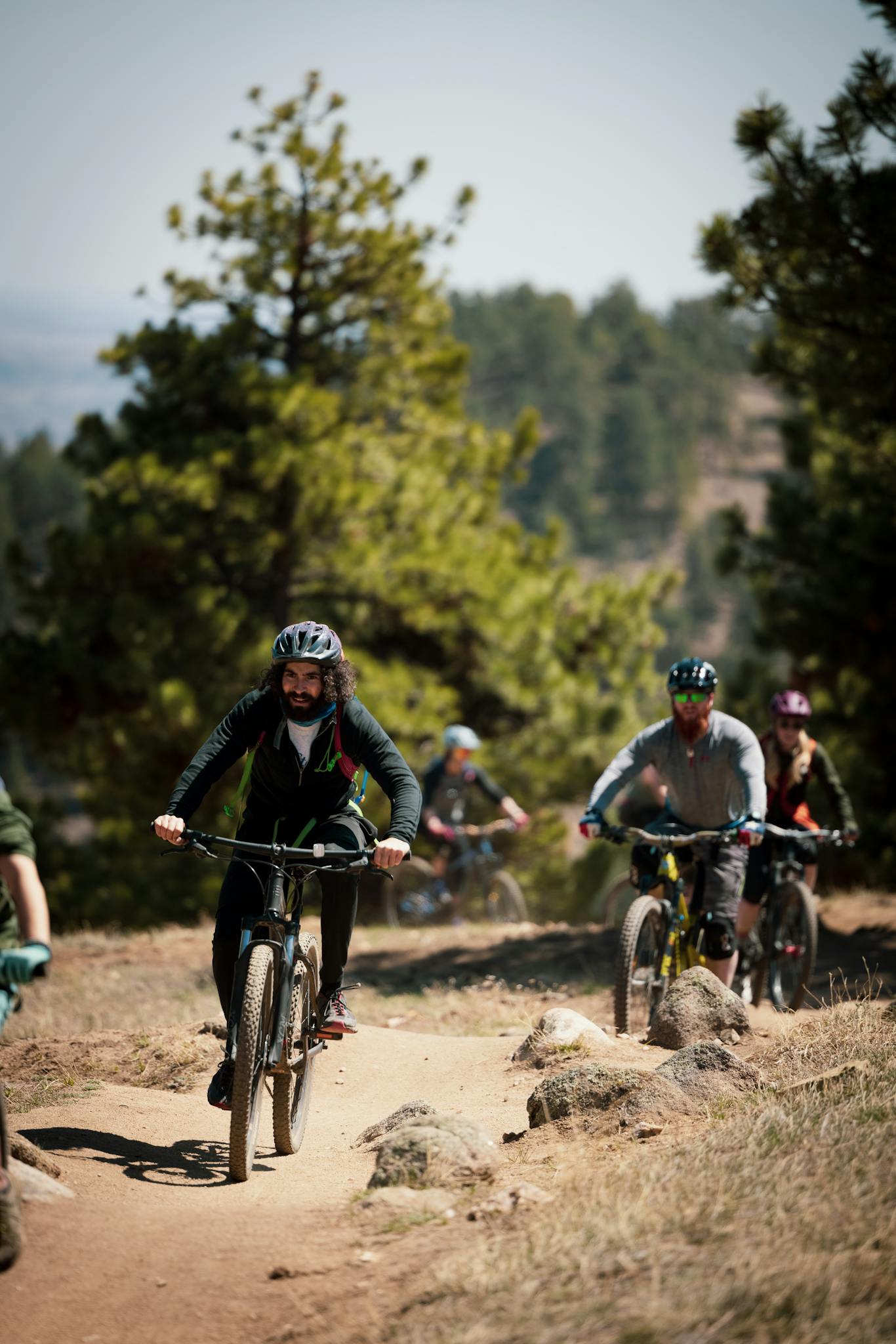 A group of mountain bikers enjoying a sunny ride on a forest trail, showcasing outdoor adventure in nature.